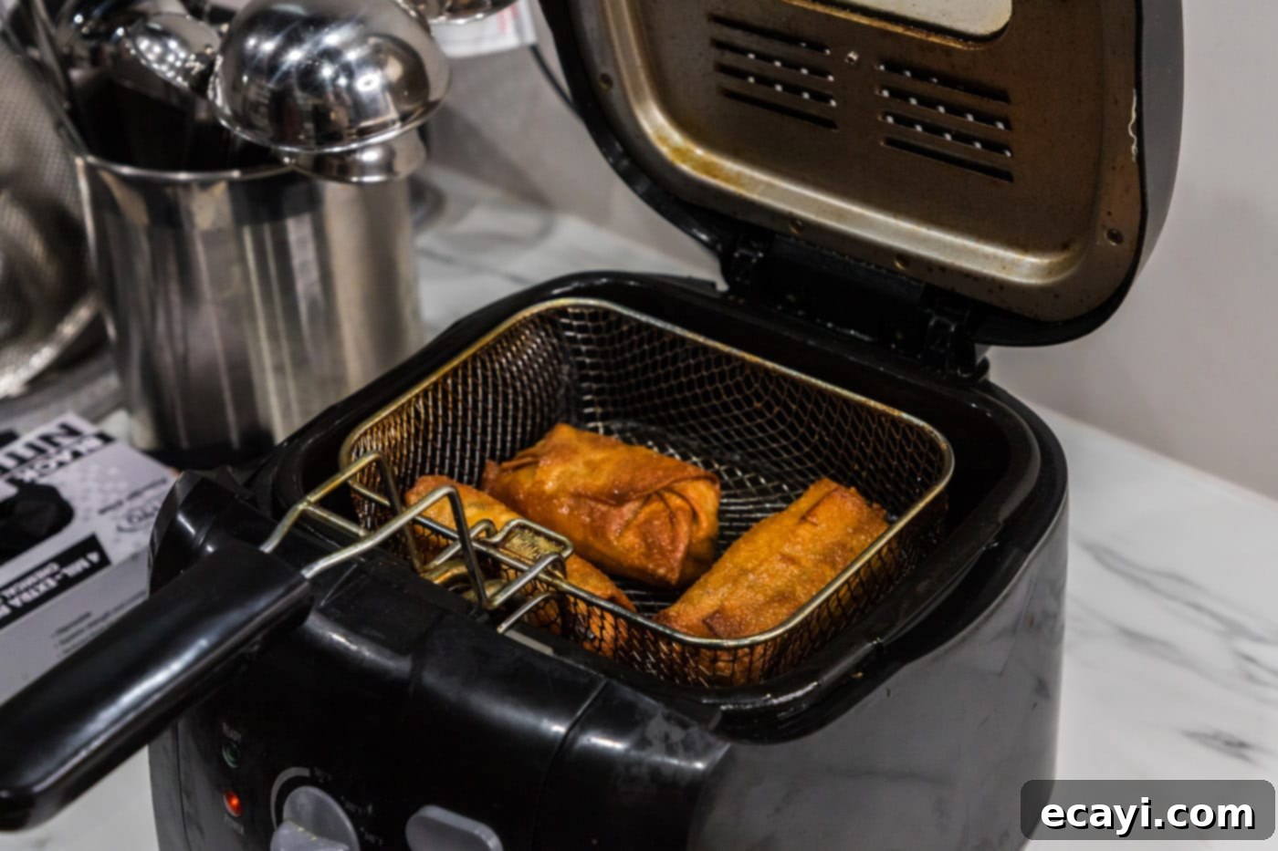 Ultimate Big Mac Egg Rolls 15 crispy, golden-brown egg rolls in a deep fryer basket, ready to be removed