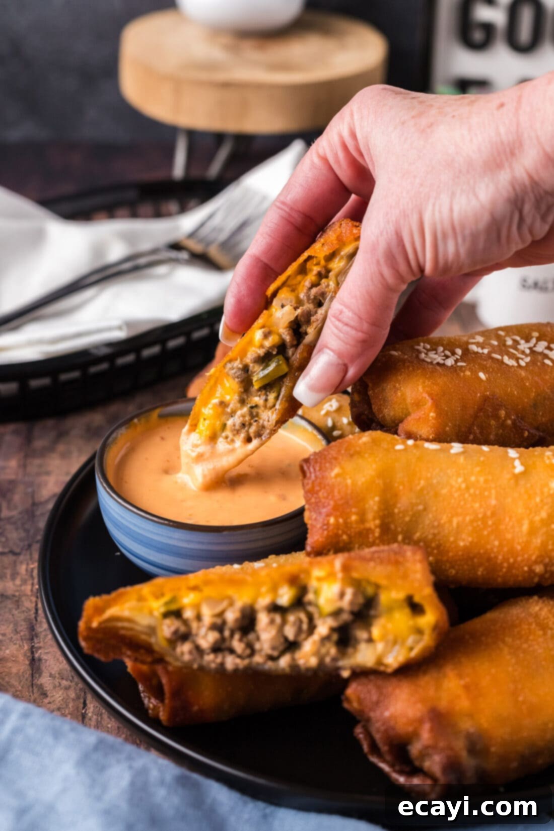 Ultimate Big Mac Egg Rolls 16 Half of a Big Mac Egg Roll being dipped in Thousand Island dressing, showing the creamy texture of the sauce