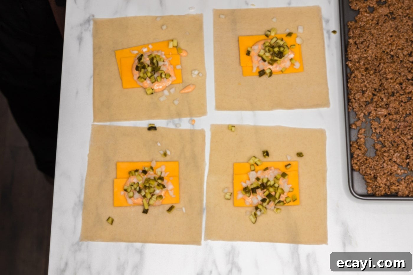 Ultimate Big Mac Egg Rolls 9 egg roll wrappers with cheddar cheese, chopped onion, and pickles neatly arranged in the center