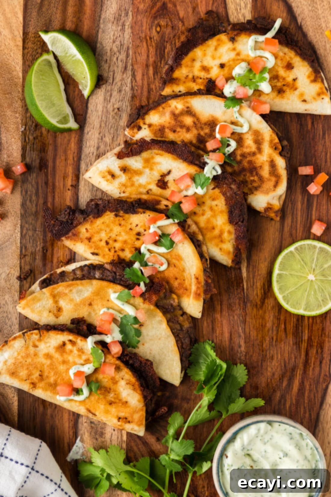 Hearty Black Bean Tacos 12 Beautifully arranged black bean tacos on a wooden board, garnished with fresh sour cream, diced tomatoes, and cilantro, ready to be served.