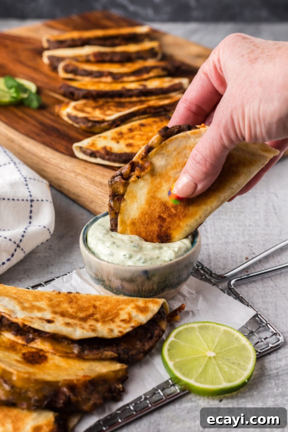 Hearty Black Bean Tacos 3 A golden-brown black bean taco being dipped into a small white bowl of creamy sauce, emphasizing its crispy texture and delicious appeal.