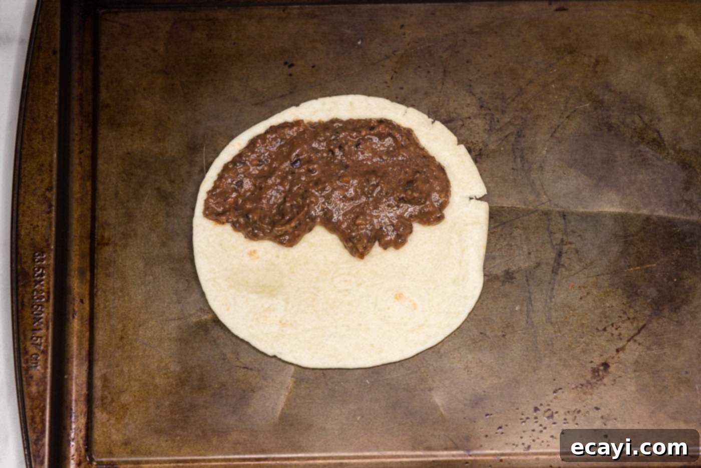 Hearty Black Bean Tacos 8 Black bean mixture carefully spread over half of a flour tortilla, demonstrating the filling technique.
