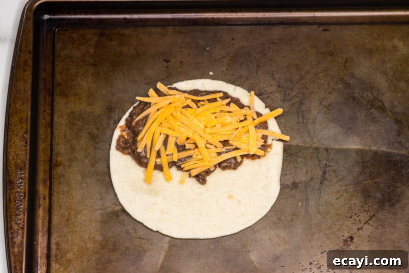 Hearty Black Bean Tacos 9 Shredded cheddar cheese layered on top of the black bean mixture on a tortilla, prior to folding.