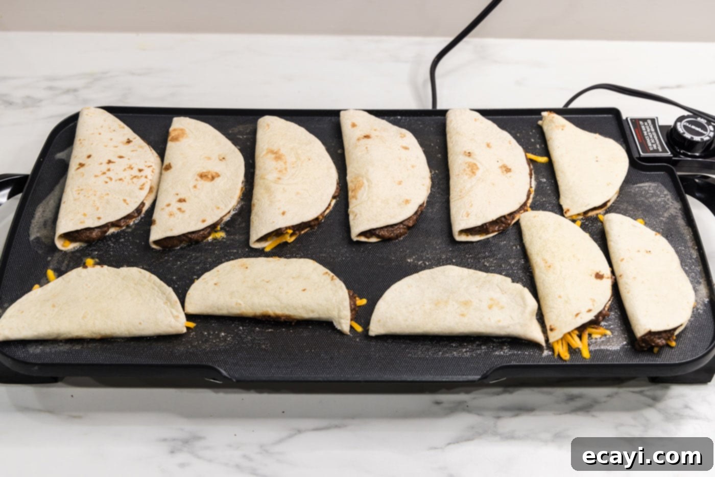 Hearty Black Bean Tacos 10 Multiple folded black bean tacos cooking on a hot griddle, starting to turn golden brown.
