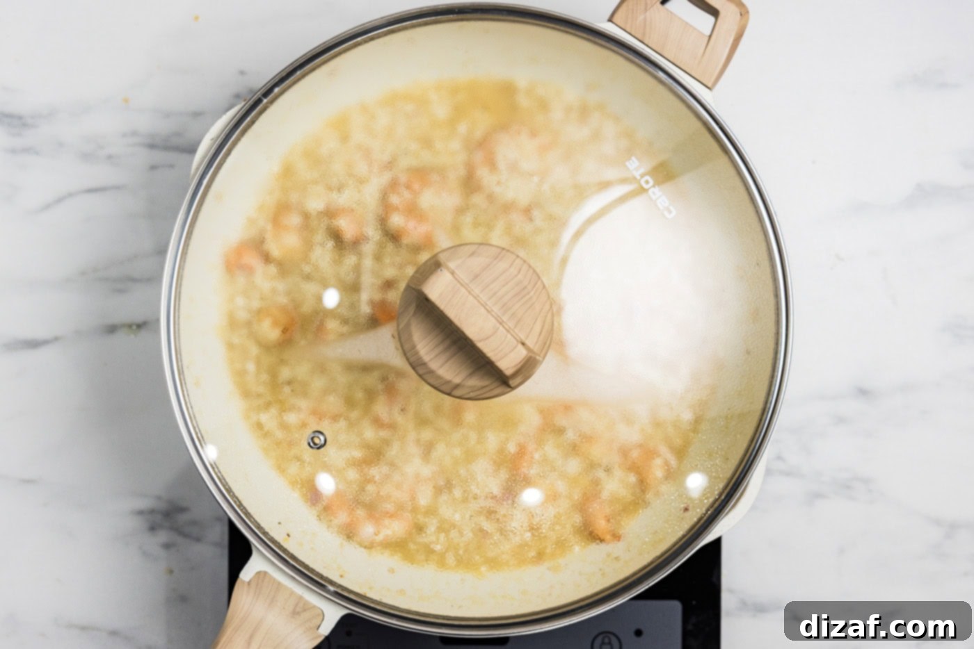 shrimp risotto in a skillet cooking with a lid