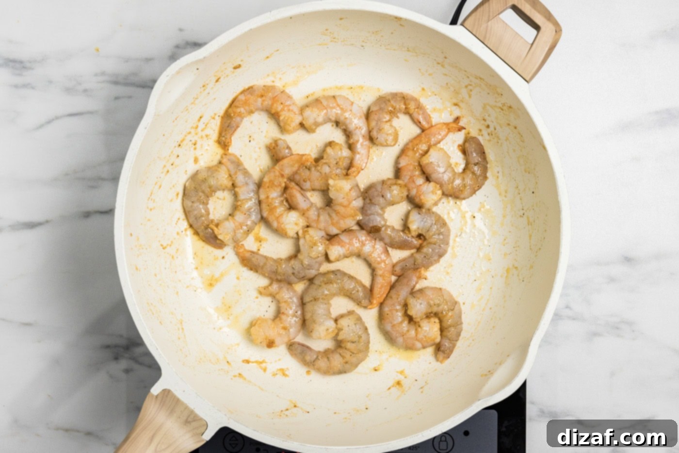 partially cooked shrimp in a skillet