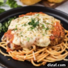 Close up photo of Veal Parmesan plated on top of spaghetti