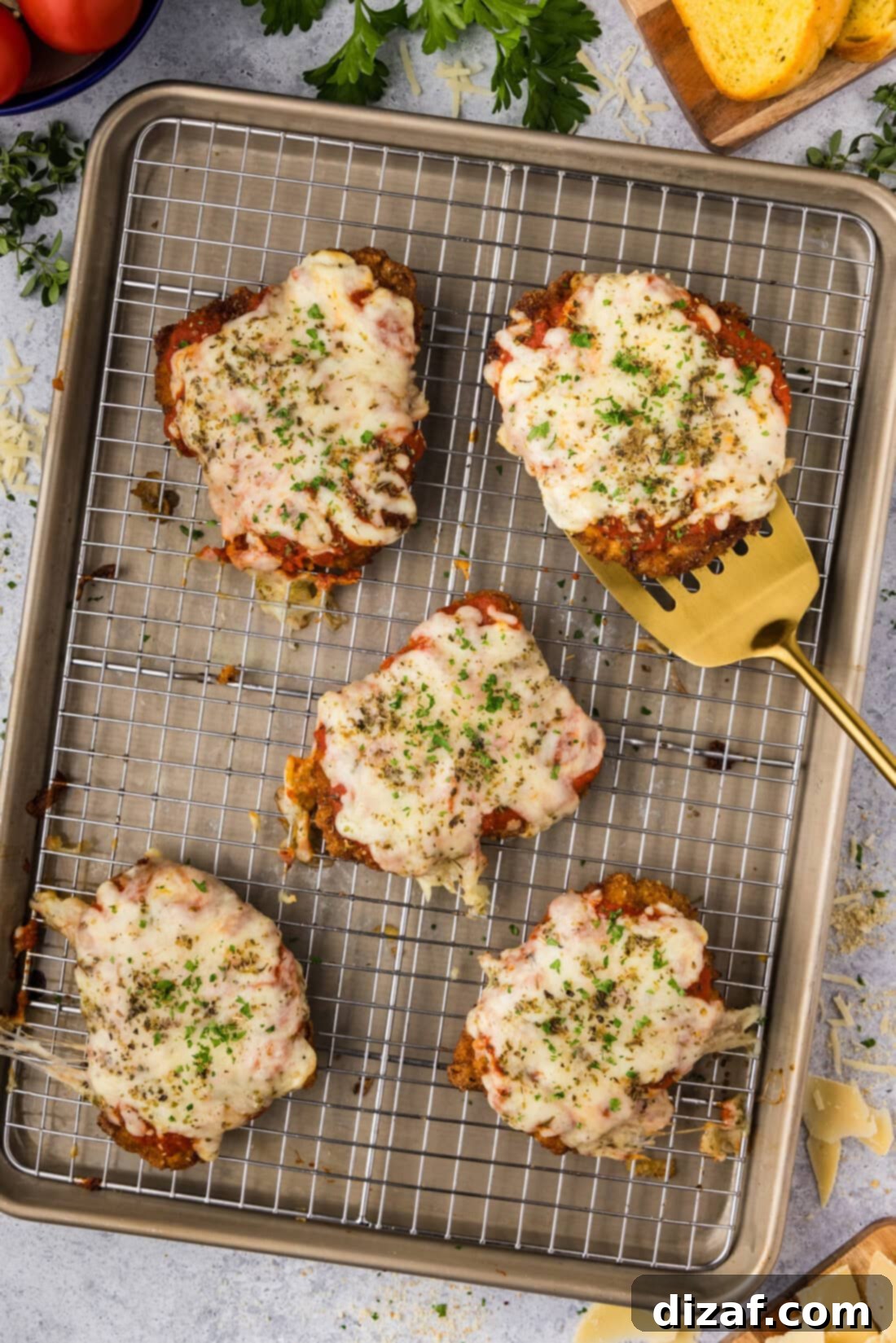 Veal Parmesan resting on a baking sheet with a spatula