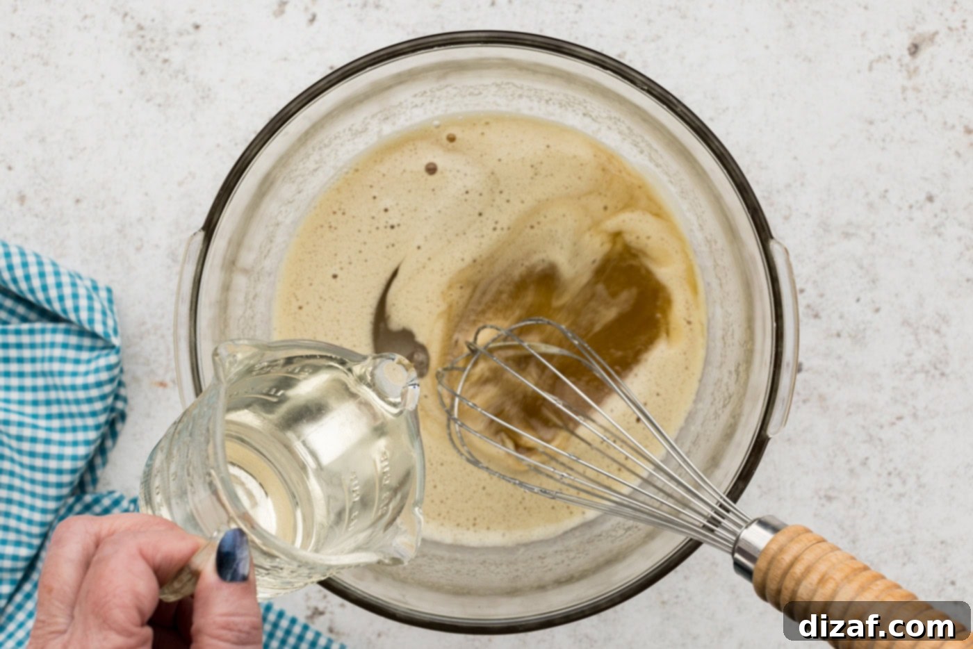pouring corn syrup into a sugar and egg mixture, beating with a whisk