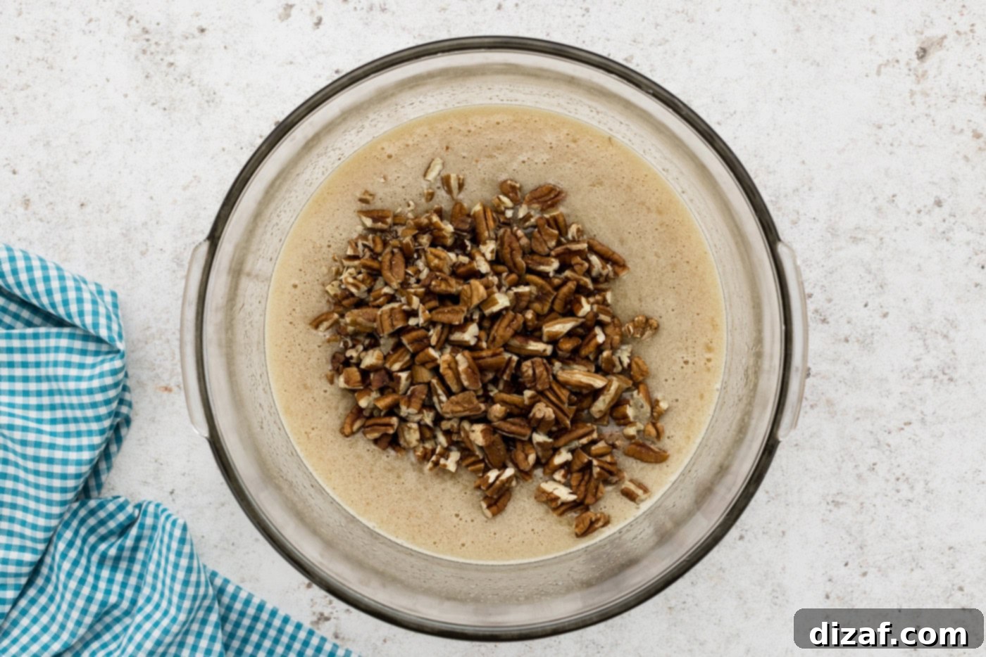 chopped pecans being added to the pecan pie filling in a mixing bowl