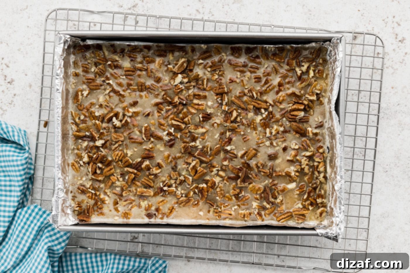 pecan pie filling poured over a shortbread crust in a baking dish