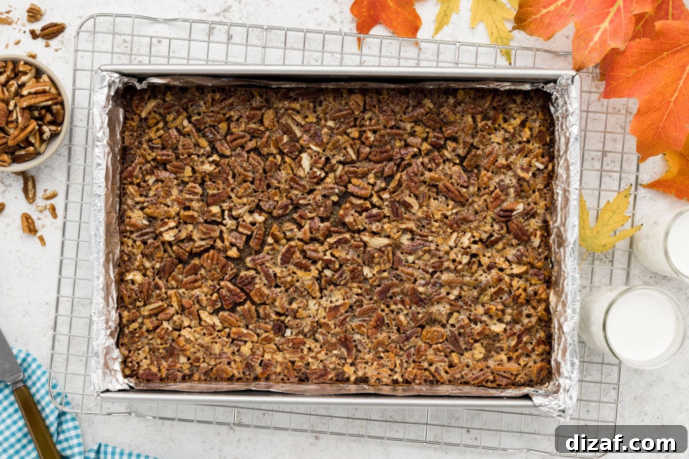 overhead photo of freshly baked pecan pie bars cooling in a dish before cutting