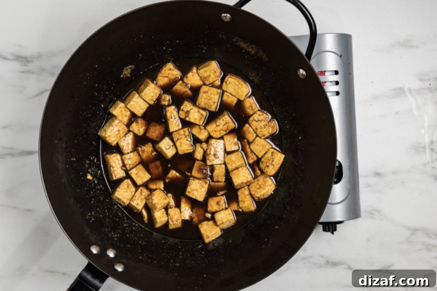 Savory Glazed Teriyaki Tofu 7 Stir-fried tofu perfectly coated in thick, glossy teriyaki sauce in a wok.