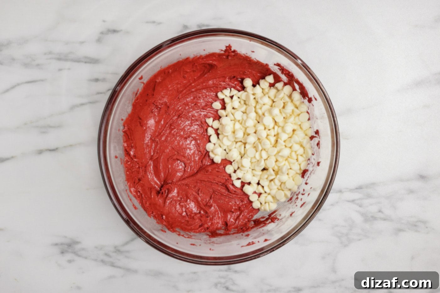 white chocolate chips added to red velvet cake batter in a mixing bowl