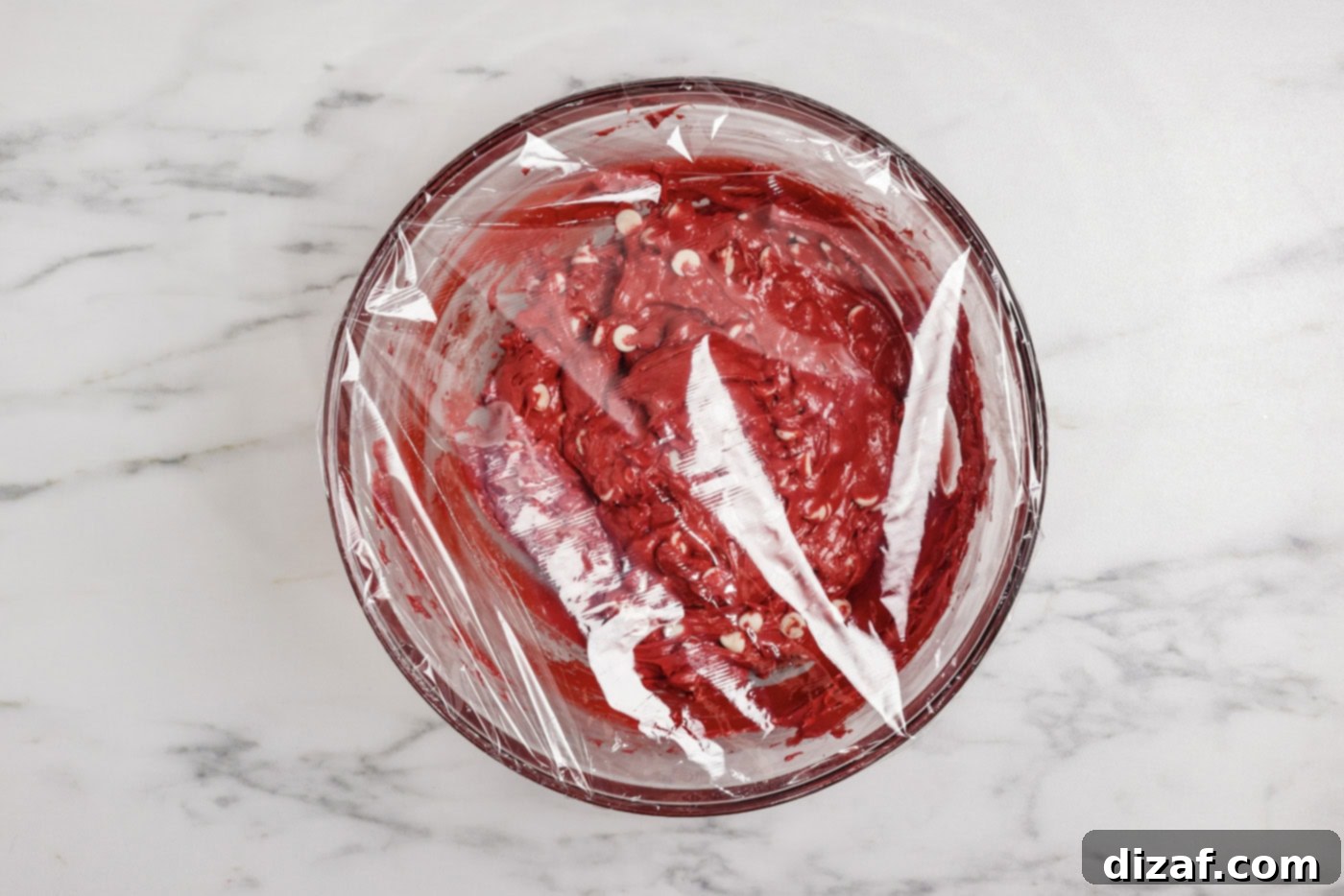 plastic wrap covering a bowl of red velvet cake cookie dough