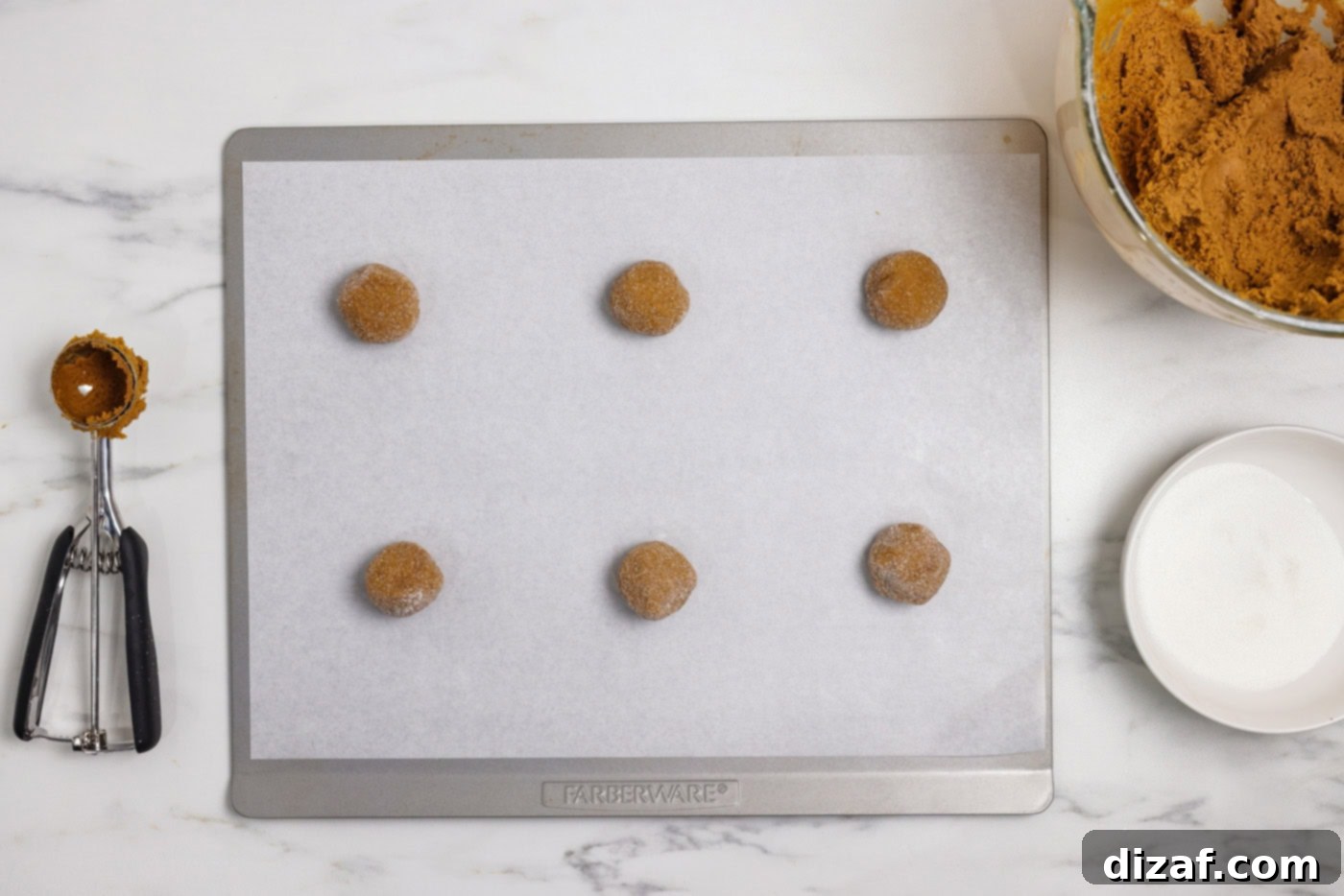 Gingersnap cookie dough balls coated in sugar on a baking sheet