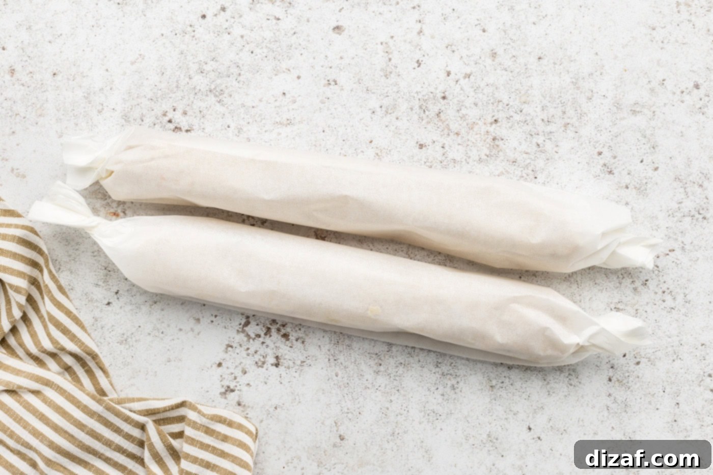 Two roll of icebox cookie dough wrapped in parchment paper