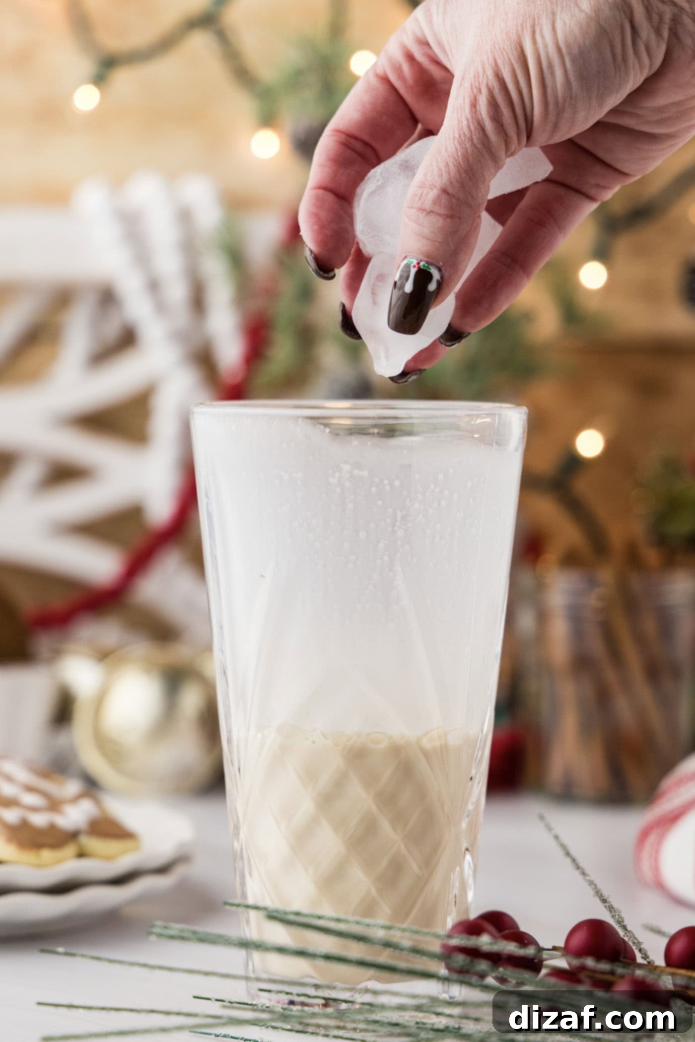 hand adding ice to a cocktail shaker with liquid