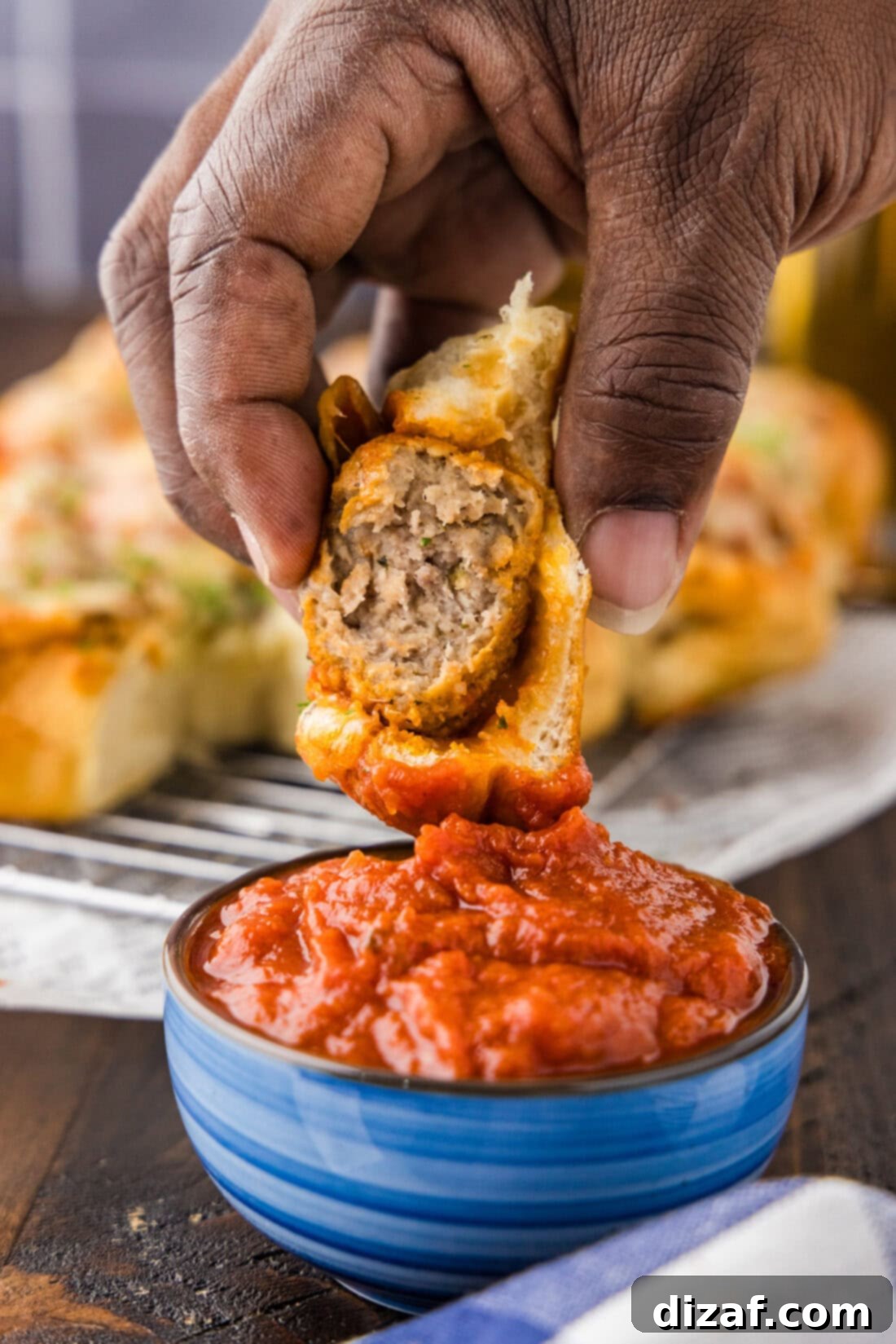 Meatball Slider being dipped into a bowl of marinara sauce, close up shot.