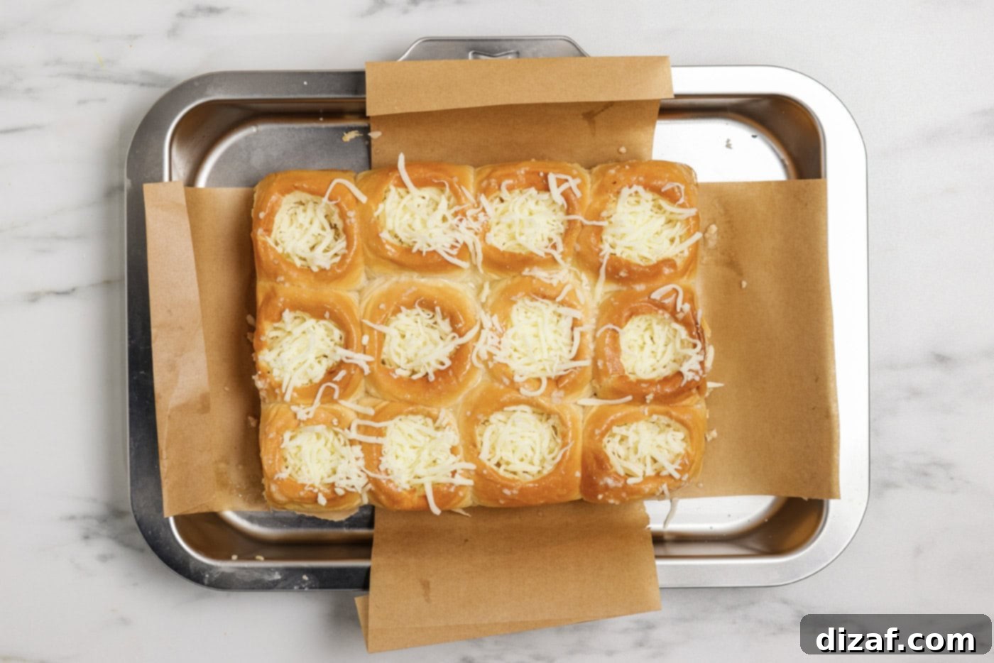 Mozzarella cheese being added to the holes cut out of the dinner rolls, ready for the marinara and meatball.