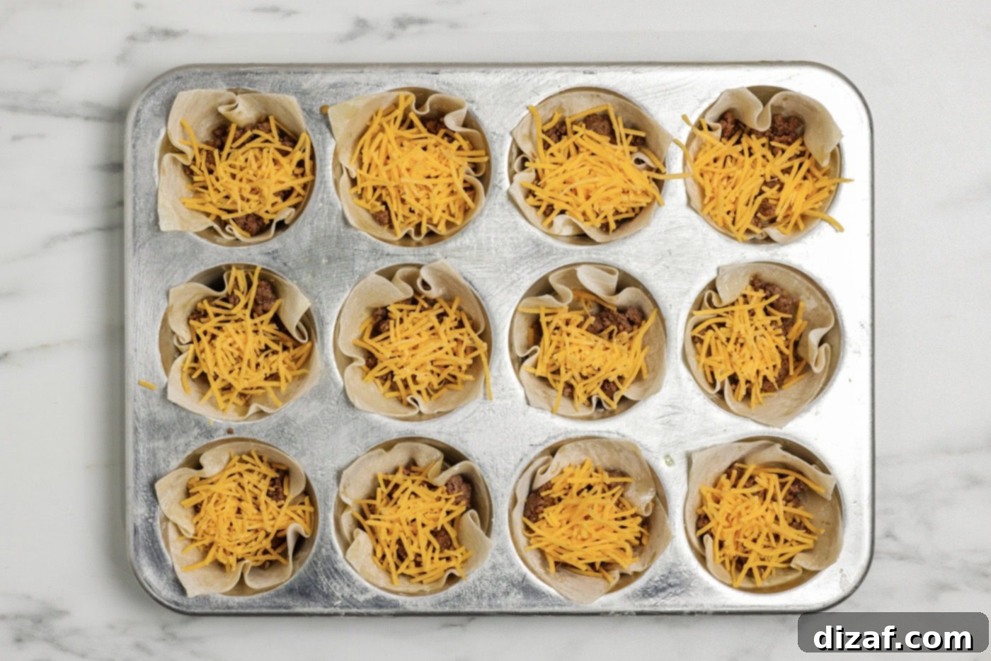 Shredded cheese added on top of the taco meat inside wonton wrappers