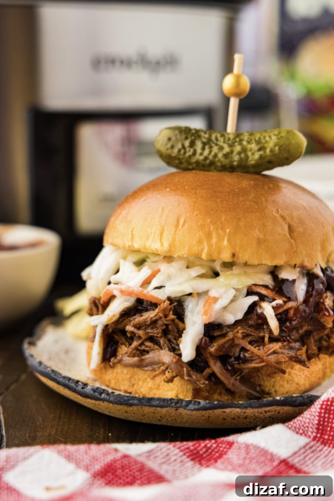 Slow-Cooker BBQ Shredded Beef Sandwiches 3 Close up photo of a Crockpot BBQ Beef Sandwich with a pickle on top