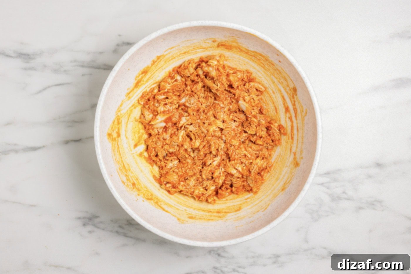 Mixing chicken with buffalo sauce