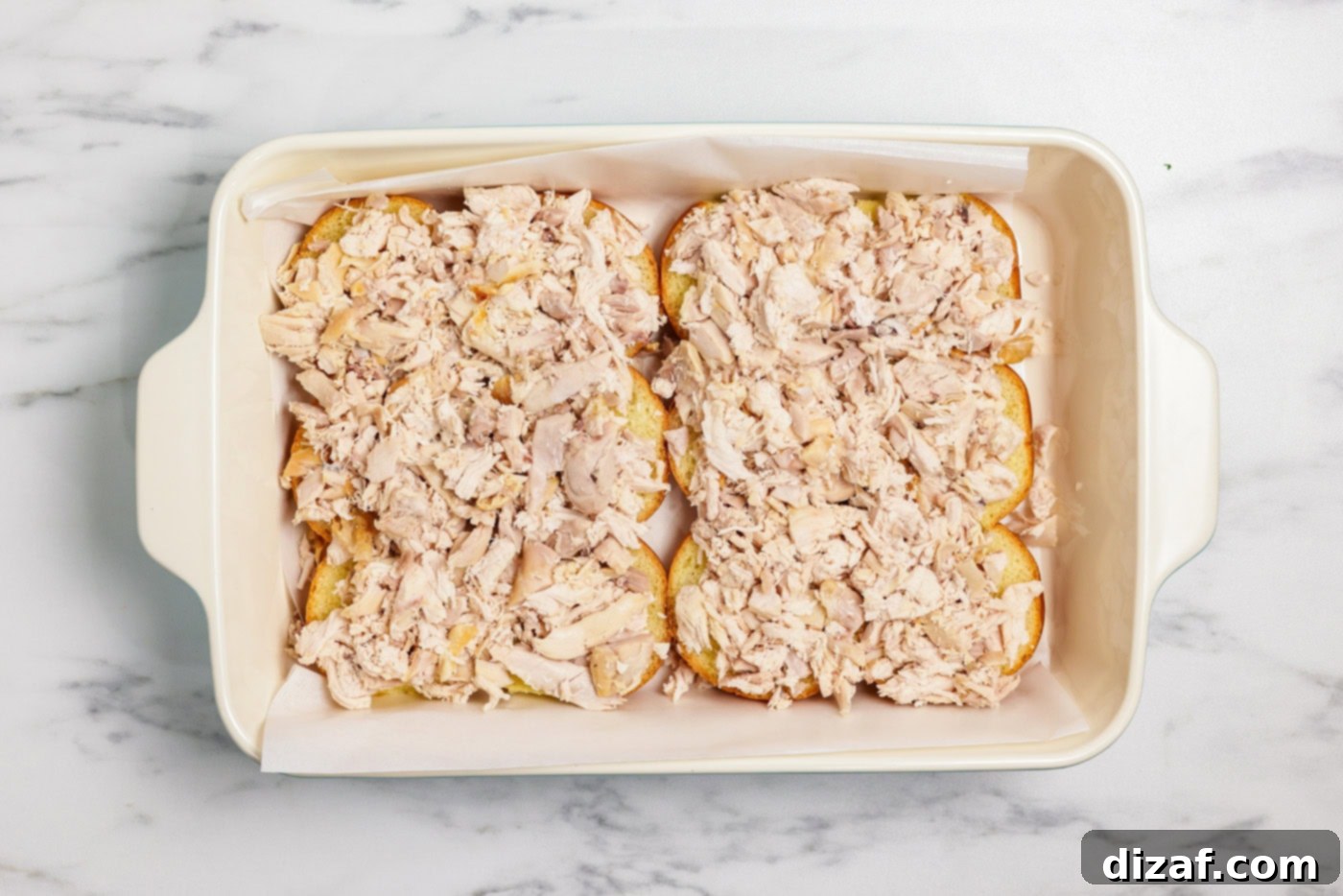 Shredded chicken on slider buns in baking dish