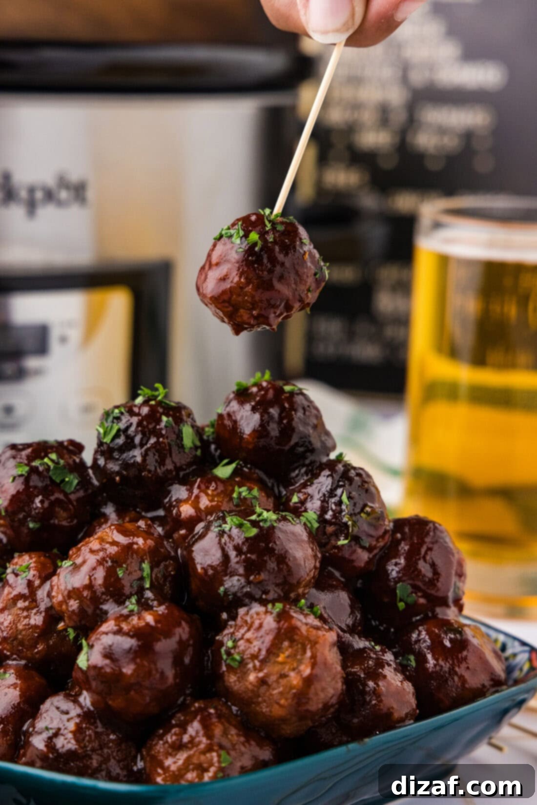 BBQ Meatballs 3 BBQ Meatball on a toothpick held above a pile of BBQ Meatballs