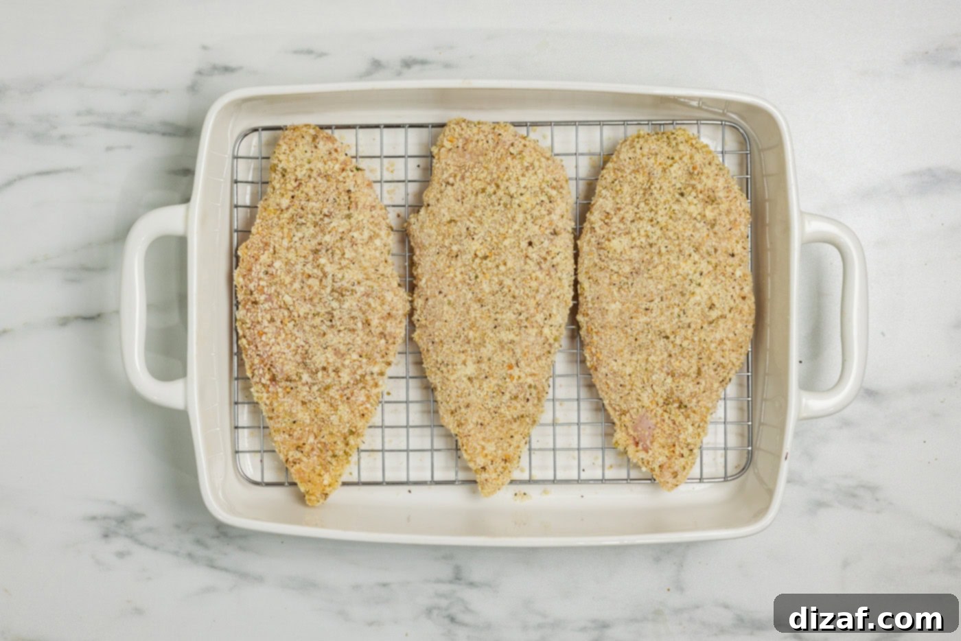 parmesan and breadcrumb coated chicken breast in a baking pan lined with a wire rack