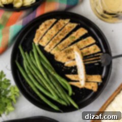 Plate of Parmesan Crusted Chicken cut into slices with green beans on the side